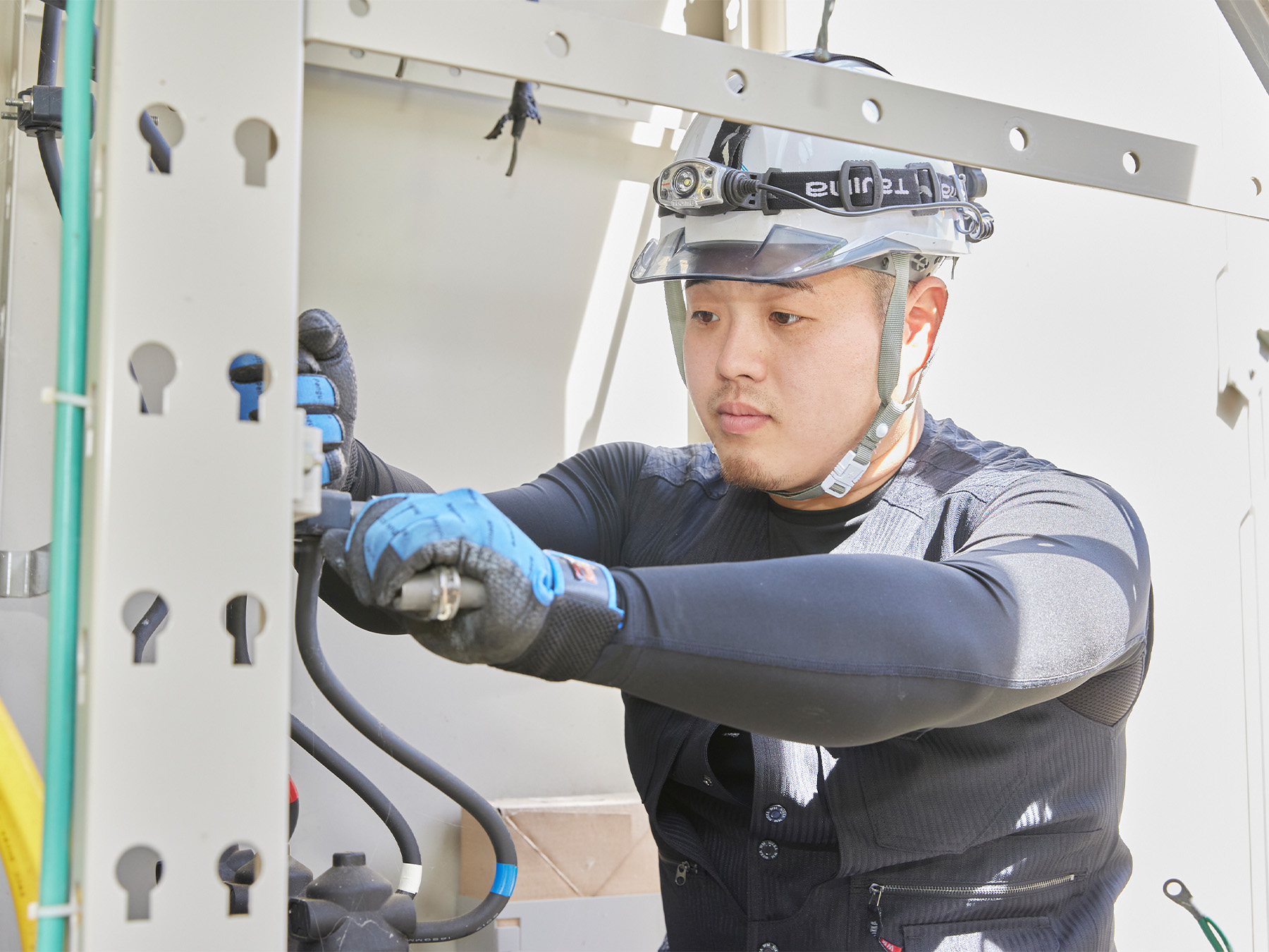 作業員が電気設備の内部で工具を使って作業をしている様子